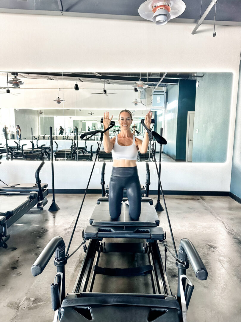 A woman is standing on a pilates machine