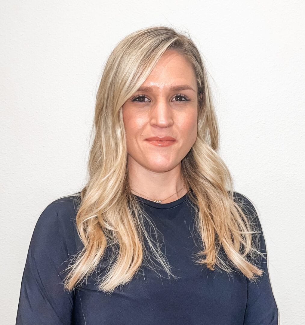 A woman with long blonde hair wearing a blue shirt.