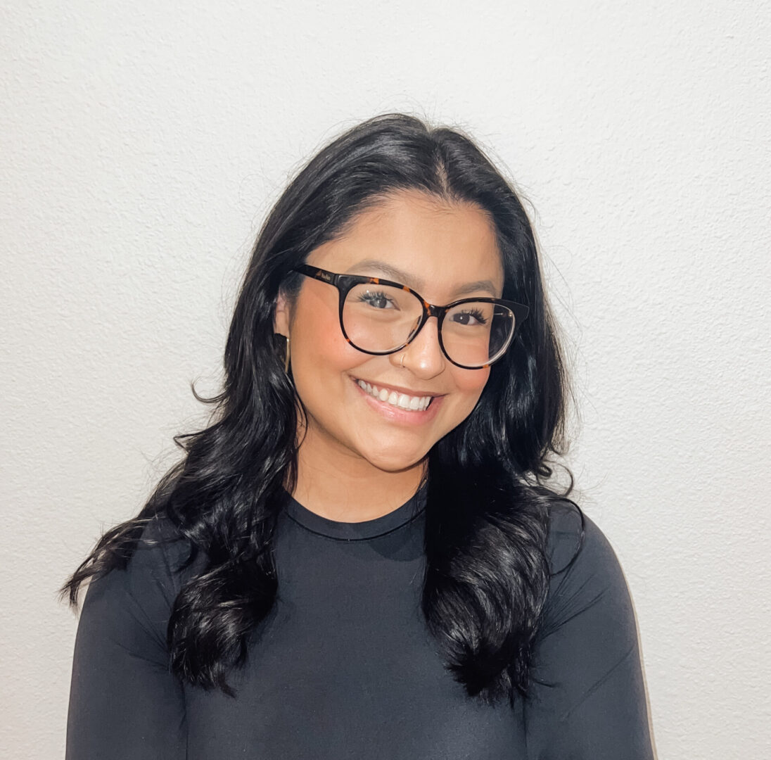 A woman with glasses smiling for the camera.